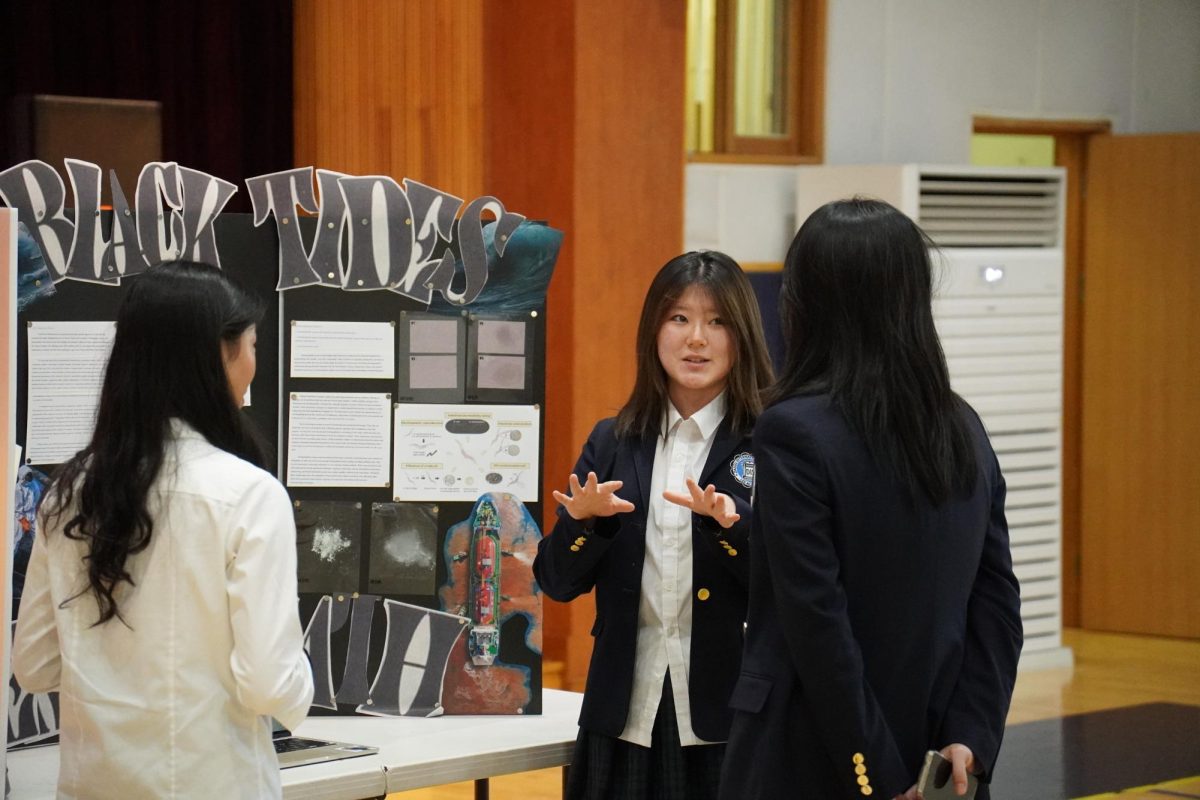 Junior Victoria Kang explains her project on ocean oil pollution and mitigation strategies. Her clear gestures and precise explanations keep the audience focused.
