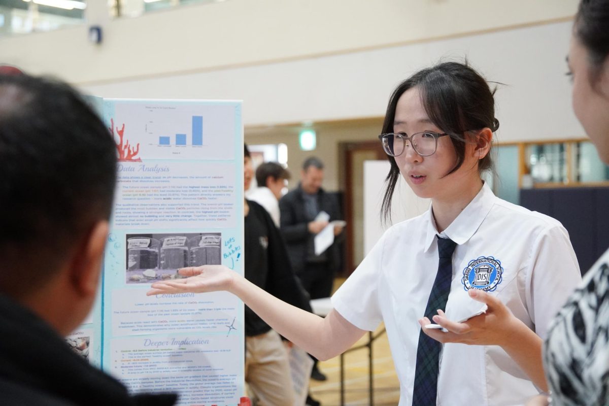Sophomore Amy Kim confidently presents her project to teachers. A clear display and organized notecards reinforce her command of the topic.
