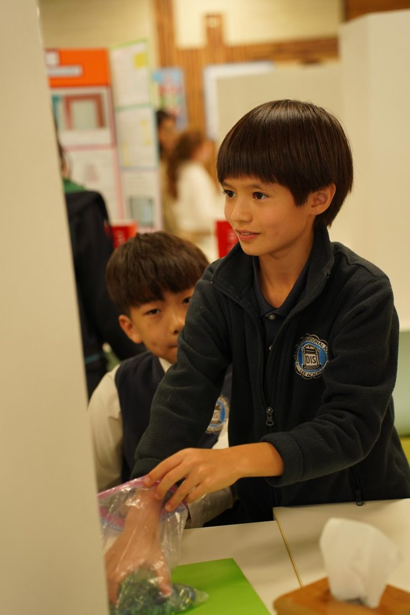 Fourth grader Luka Gall engages with hands-on materials at the fair, leaning in to explore the exhibit firsthand. His focused expression reveals an emerging interest in the science behind the display.