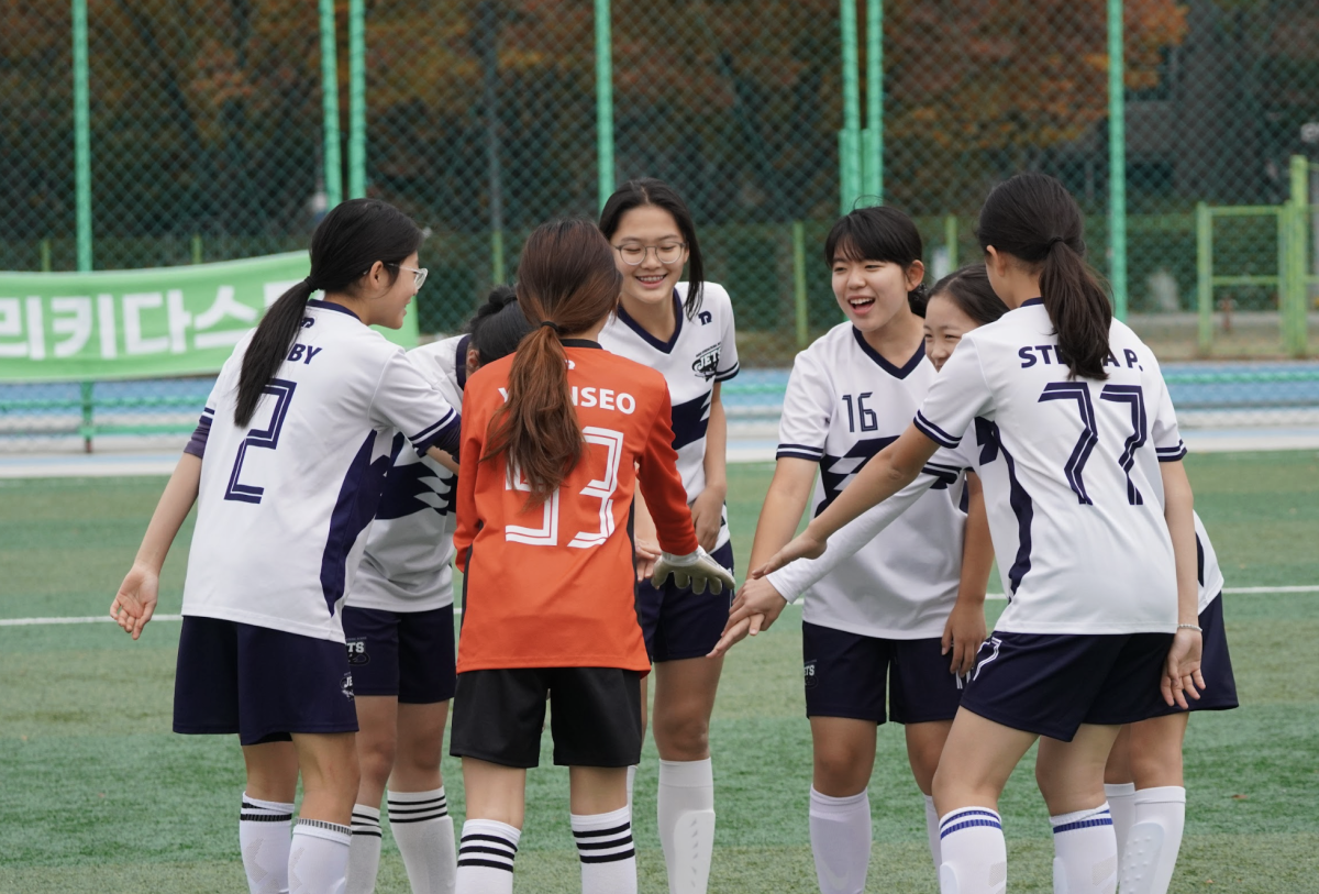 The junior varsity girls crank up the hype with a pre-game chant. The turf buzzes with a full-charge atmosphere as the starting members take their positions. 