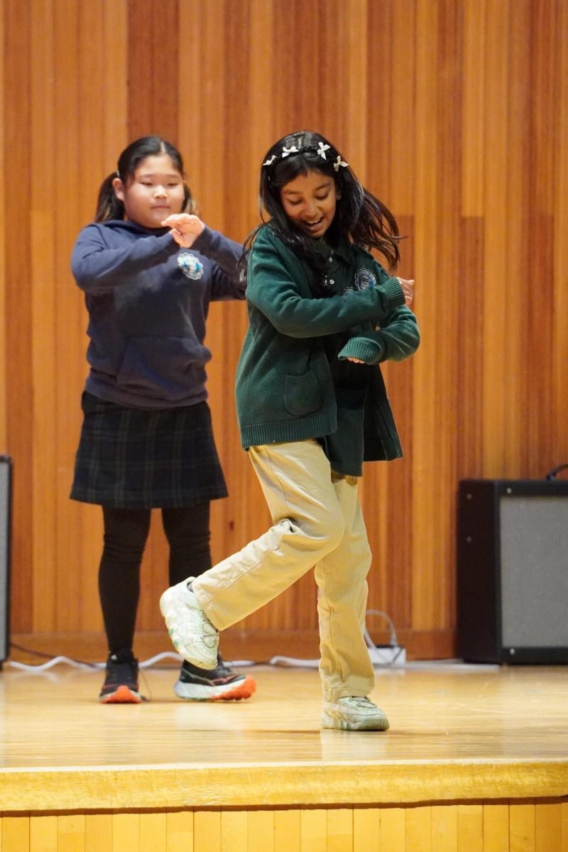 Fourth graders Violet Lee and Maha Rahman perform as members of the Beat Bunch, moving in sync as they carry the choreography across the stage. Their coordinated steps and timing reflect the group’s preparation as they progress through the routine. 