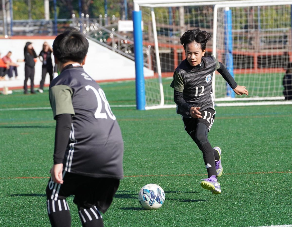 Louis Lee in fifth grade dribbles the ball effortlessly as his teammate eagerly waits for the crucial pass to score the game to seal the victory.