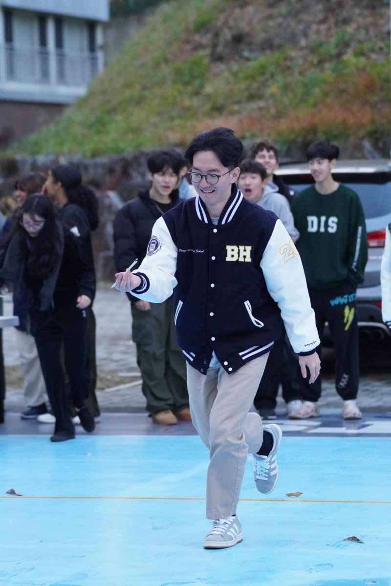 Senior Brandon Hyun clenches his teeth as he carries a bean with chopsticks during the relay game. His steady stance and precise steps impress the juniors cheering behind him. 