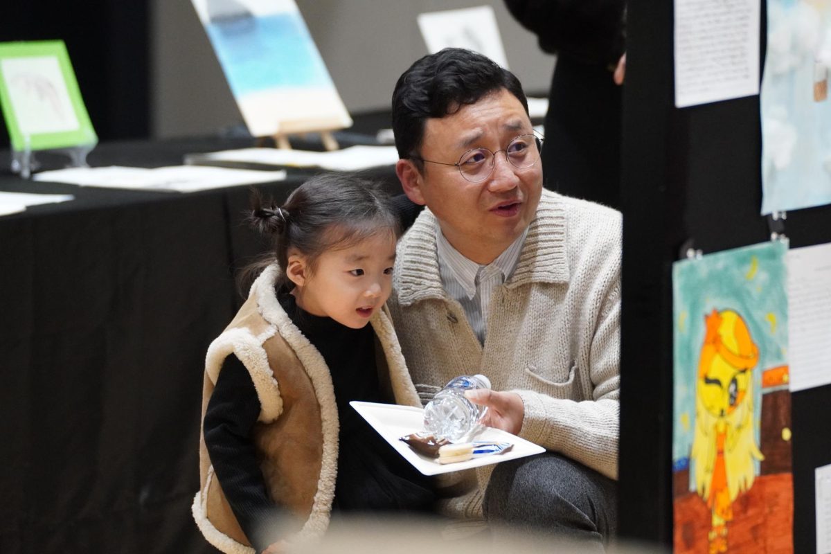 Mr. Jack, Director of Facility Planning and Faculty Housing, and his daughter scoot down around an art display to lay out compliments. While amusing the details of the pieces, they also take a look at the artists’ draft processes.