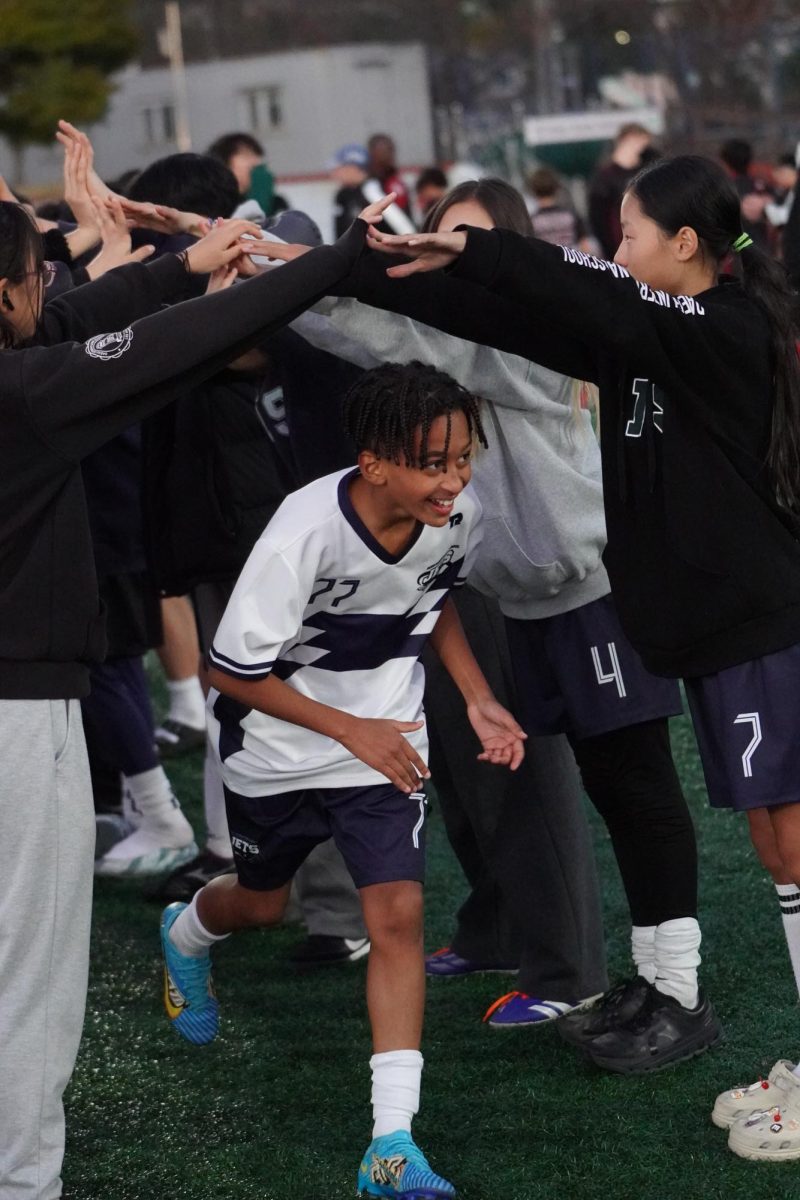 The middle school girls’ futsal team creates a celebration tunnel for the boys’ victory in the SKAIS championship. Midfielder Arthur Silva (77) sprints through with a proud beam.