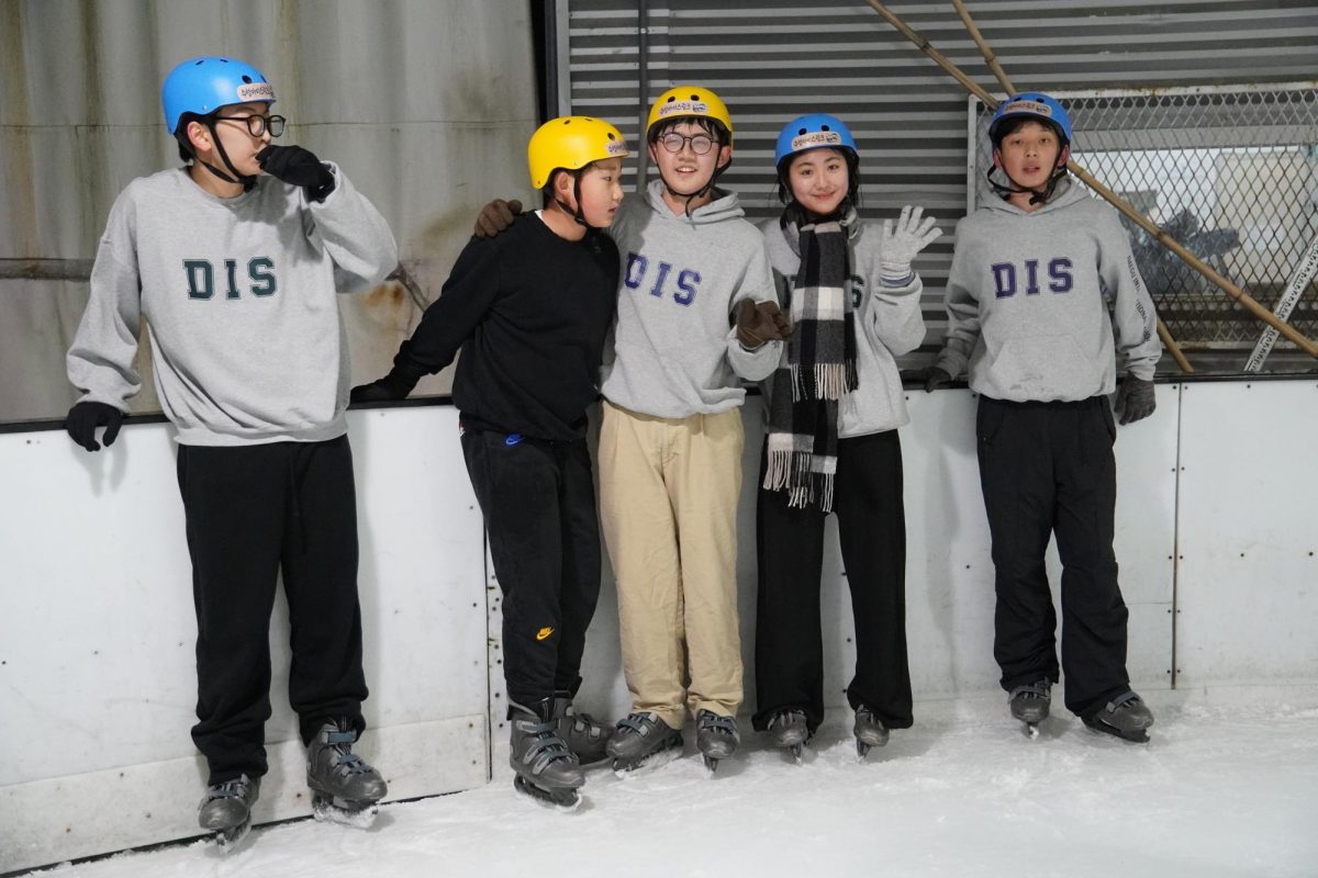 A cohort of eighth graders takes a brief break between their skating rounds. With cheeks flushed from the cold, they pause to catch their breath and enjoy the time together. 
