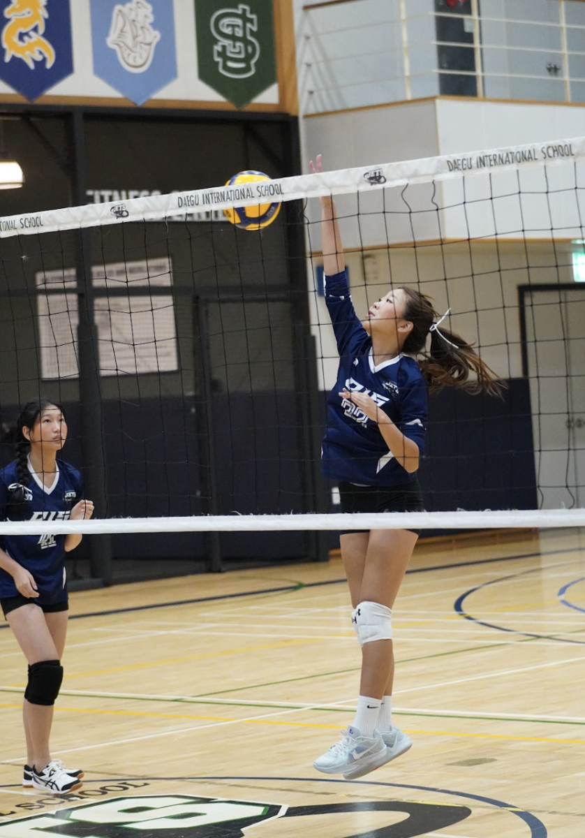Junior Sophie Lee (22) rises at the net during warmups, reaching high to time her spikes with precision. Her controlled approach and extension set the rhythm for the offense before the match begins.
