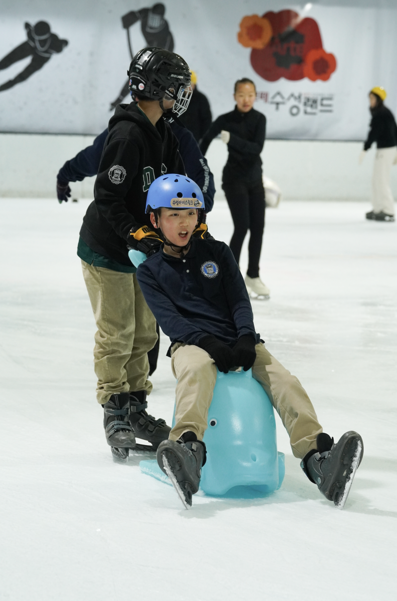 Sixth grader Robert Koo rides across the ice on a skating aid as a friend gives him a push from behind. His expression captures the moment when the ride goes a little faster than expected. 
