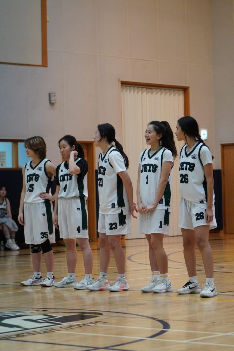 Varsity starters for the Jets step forward as Athletic Director Mr. Bergan announces their names through the gym, prepared to set the tempo from the opening tip. Before taking the floor, the girls exchange respectful handshakes with the opposing coach, underscoring the sportsmanship that defines the matchup.