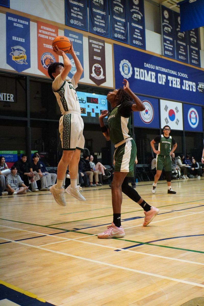 Power forward Brandon Hyun (11) creates space and rises for a smooth fadeaway jump shot. He shows confidence and control as he releases the ball over the defender.