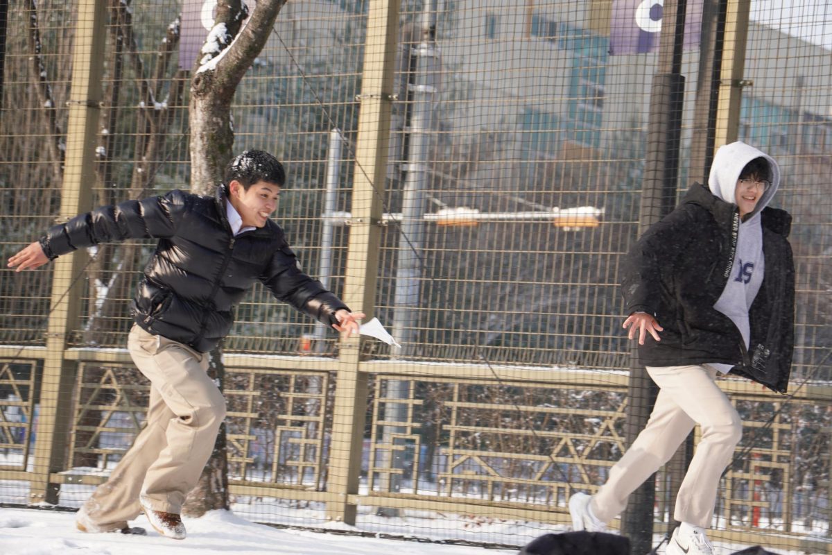 Senior William Seok chases classmate Andy Kang with all his might. Seok aims to dump snow on the only dry senior on the field. 