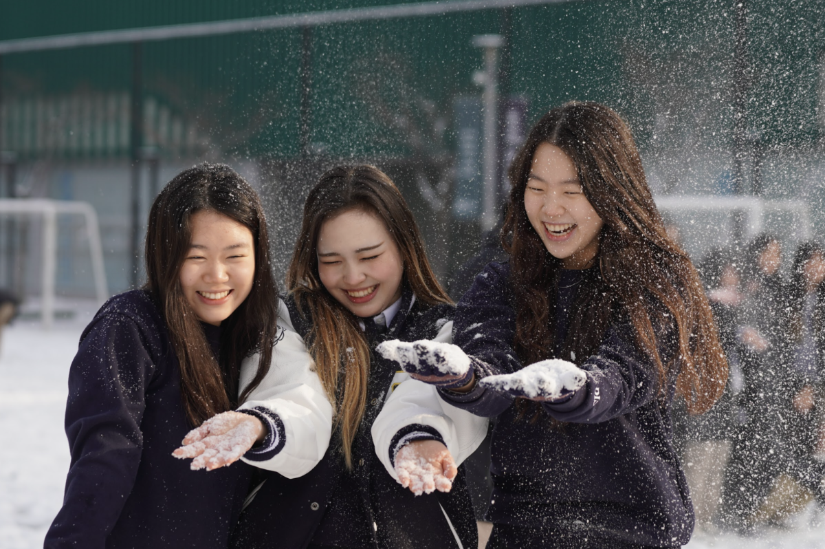 Senior Christine Mason and juniors Leewen Wang and Belle Kim giggle as snow flutters around them. Excited by the snowfall, the trio tosses handfuls of snow at one another, brightening the chilly day with laughter. 