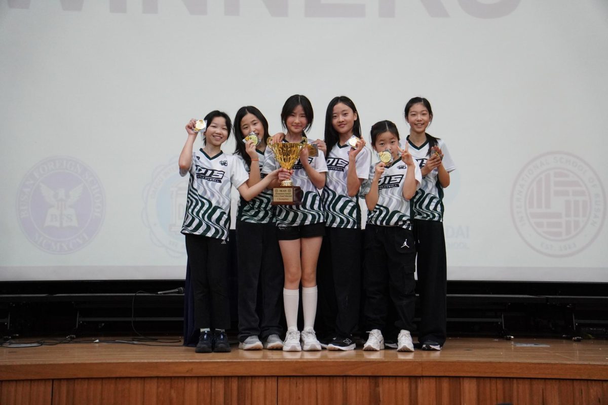 After a hard-fought tournament, the girls’ volleyball A1 team sprints to the stage to claim their trophy. Their medals glint under the lights, reflecting a culmination of hard work and talent.