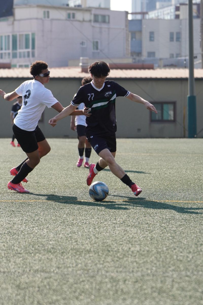 Right wing Jayden Lee (77) fends off an aggressive defender to protect possession. Despite the heavy contact, Lee (77) powers through for a scoring opportunity.