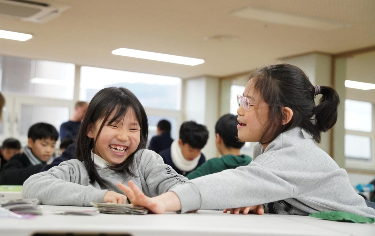 Grace Kim and Wonnie Jang in first grade share a playful moment as they go head-to-head in a board game. Kim reaches for a card, only to realize that Jang eliminated all possibilities for a victory.