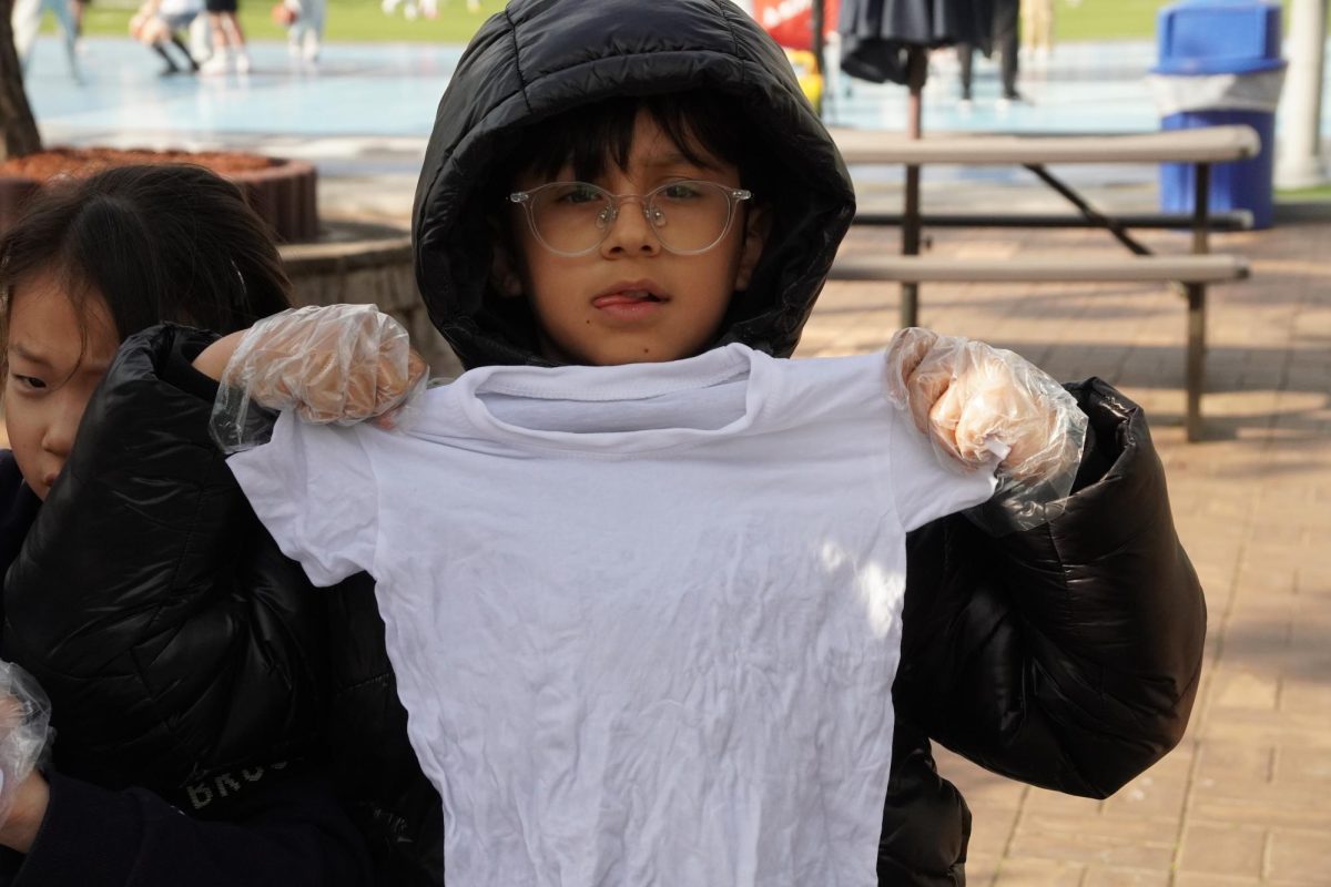 Imran Makhamatzhanov in fourth grade holds up his customized tie-dye t-shirt, taking in the finished result. The vibrant design sets it apart from the rest. 
