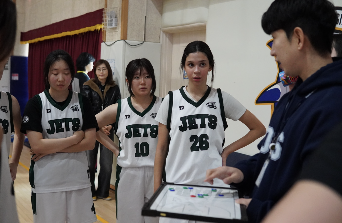 DIS gathers during halftime as Coach Park outlines a new defensive strategy to counter the Eagles’ aggressive play. The team listens closely while regrouping and adjusting their approach for the second half.