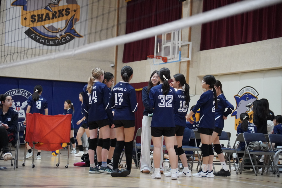 Members of the JV1 team gather in a huddle as student coach Leewen Wang offers guidance during the match. She encourages the girls to play confidently on the court.
