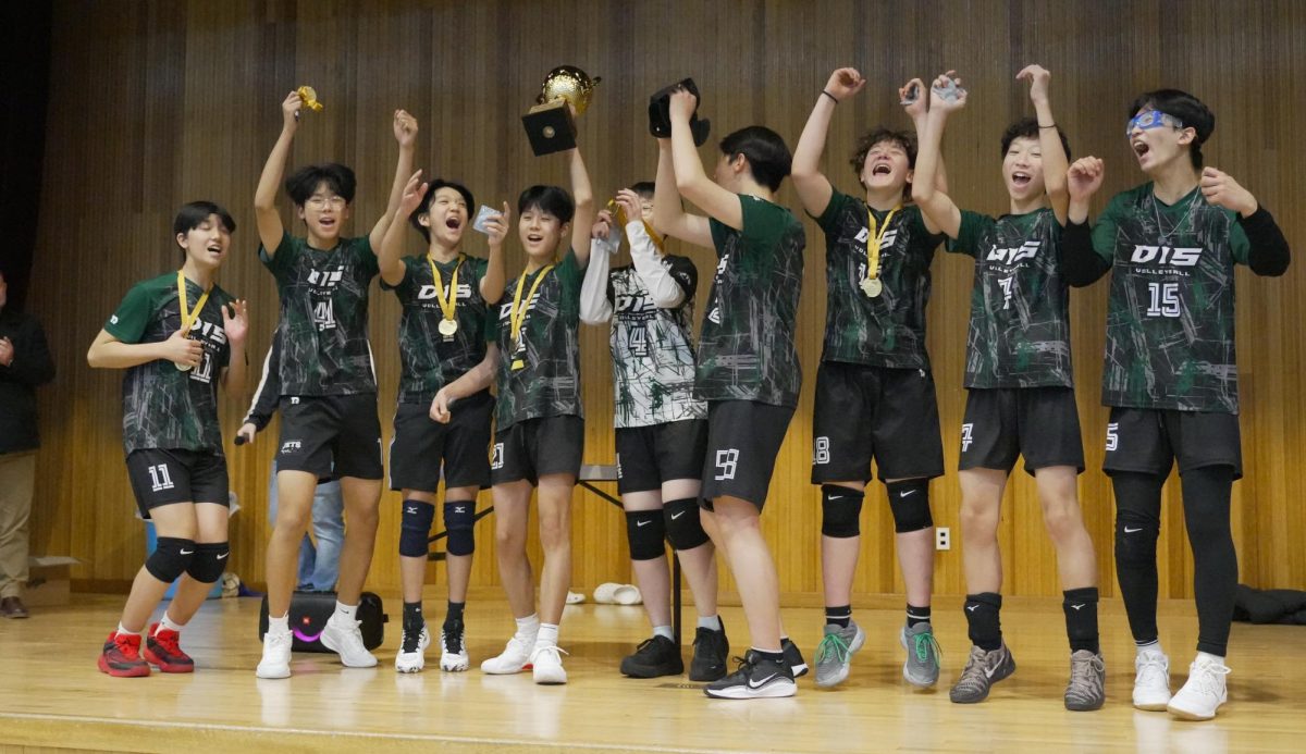 The varsity boys volleyball team erupts in cheers as they step on stage to receive their well-deserved championship trophy and medals. Coach Jolly and student coach Alex Seo stand proud of the effort the boys poured in. 
