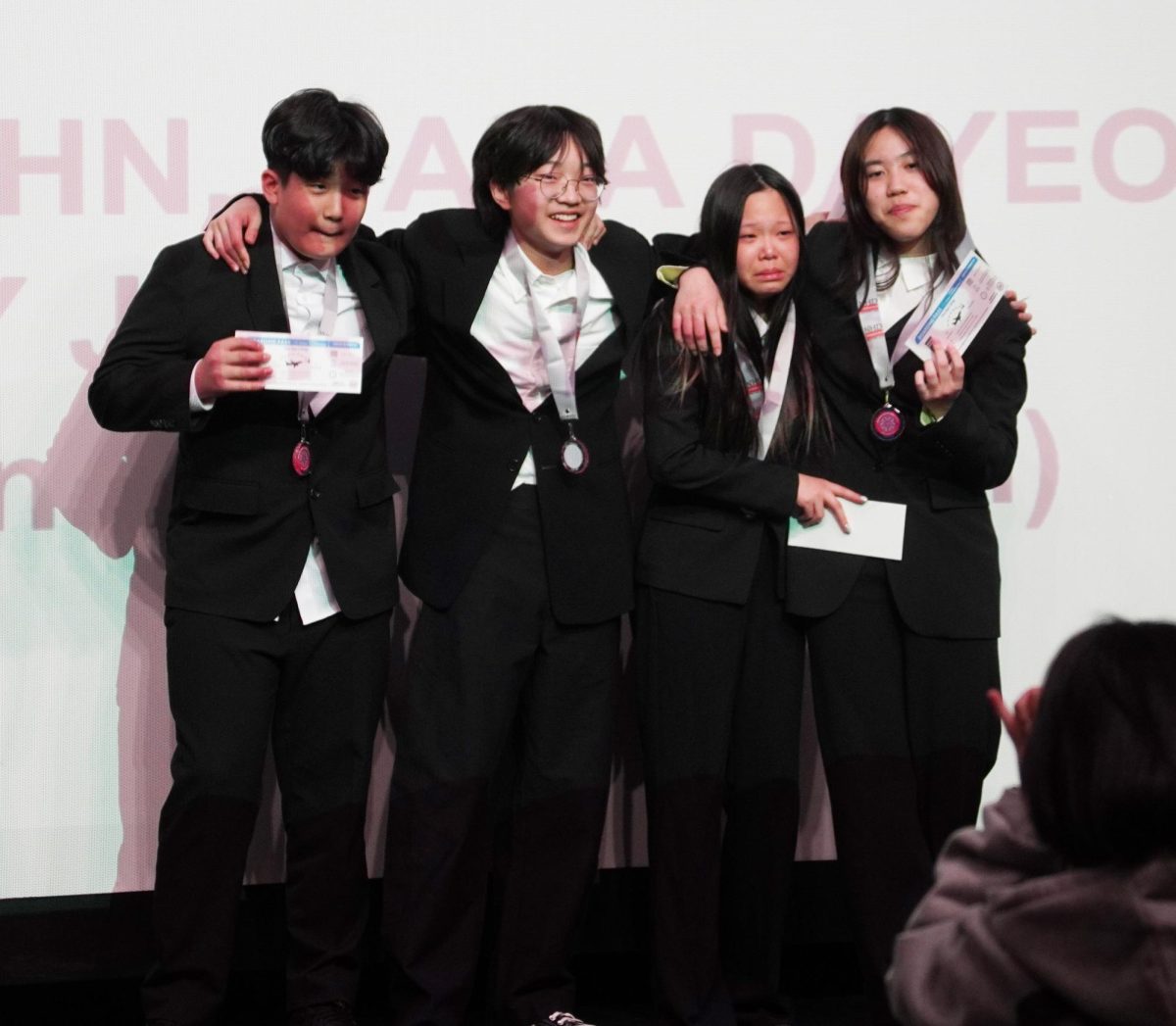 Seventh-graders Jay Jang, Gaaon Kim and Kyla Ahn, still shocked by their win, take a moment to process the victory while Dana Lee weeps from joy. “Sitting in the auditorium felt like the ceiling would collapse,” Lee said. “I was already ready to cry if we weren’t the winners, but when we won, I couldn’t believe it and how proud my parents would be.”
