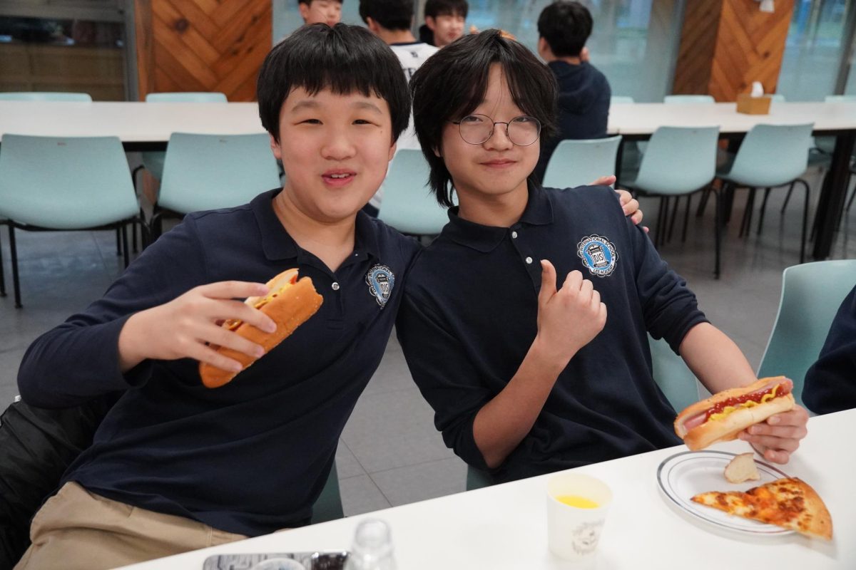 Seventh graders Dylan Li and Gaaon Kim savor their pizza and hot dogs, recharging for the next station of activities. Satisfied with the meal, Li drapes an arm over Kim’s shoulder, a gesture that reflects their strong camaraderie.