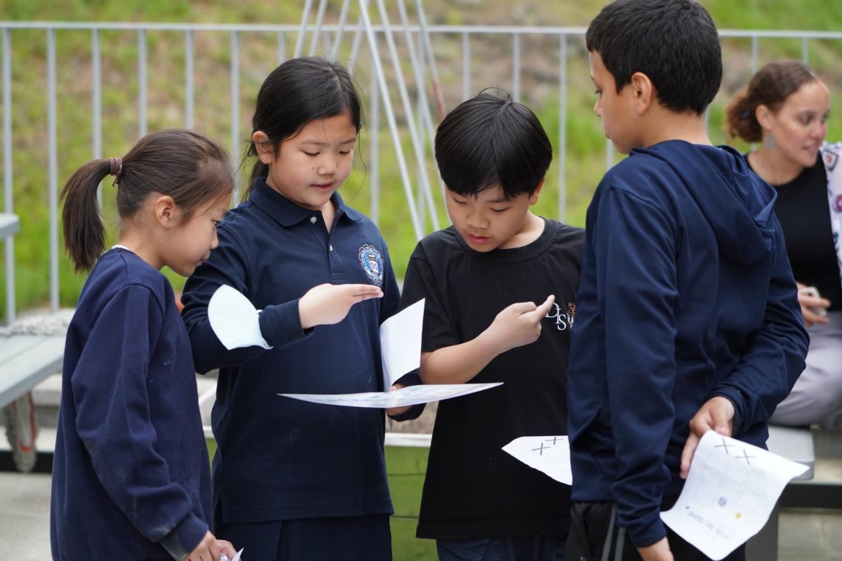 Fully focused, a cohort of elementary schoolers huddle around the sign language chart in search of their next clue. Working together, they carefully spell out their names in sign language for a chance to earn the final prize.