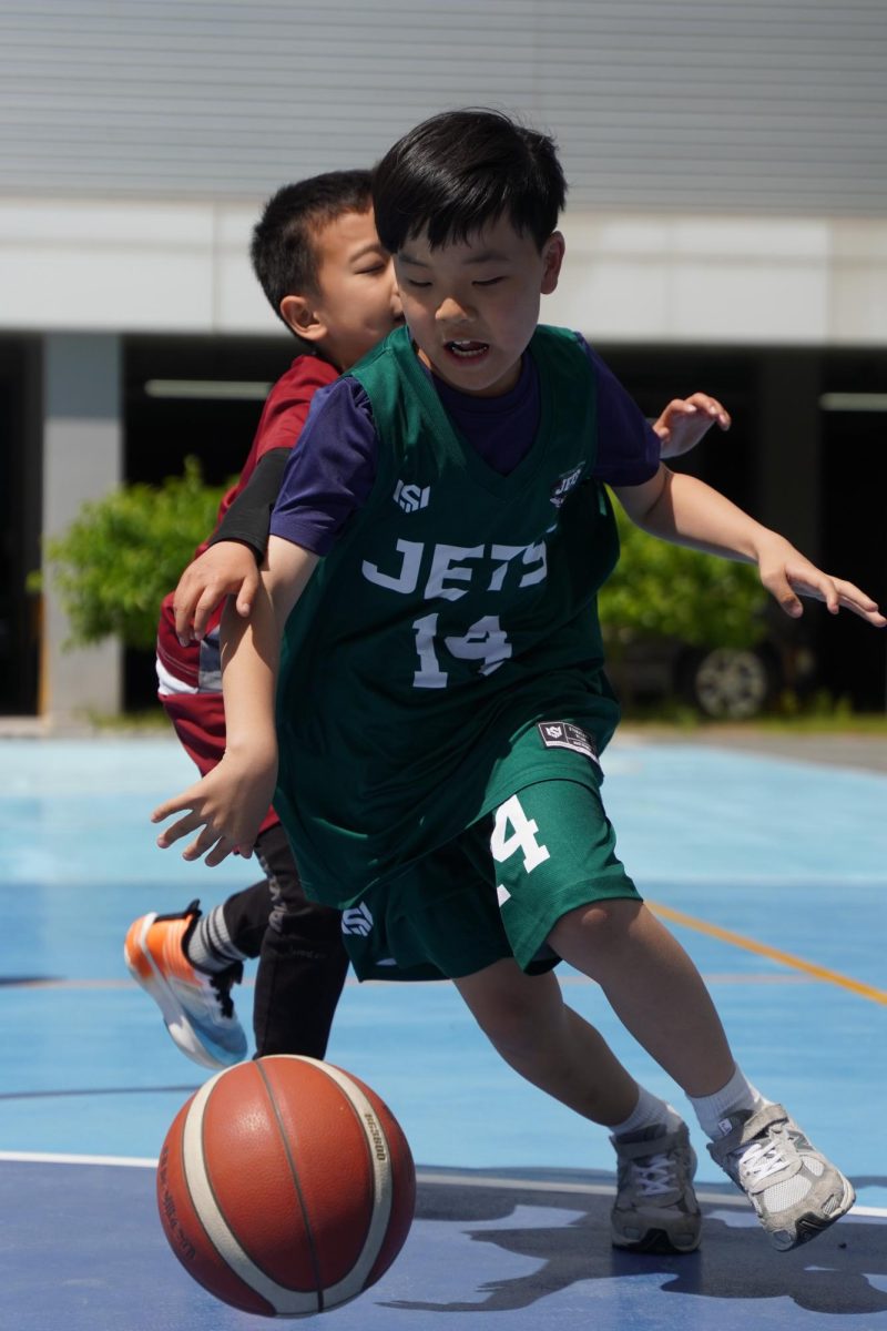 Third grader Lucas Lee drives past his defender while keeping the ball low to the ground during an intensely close match. Lee leans into the play and powers forward as the trailing defender struggles to keep up. 