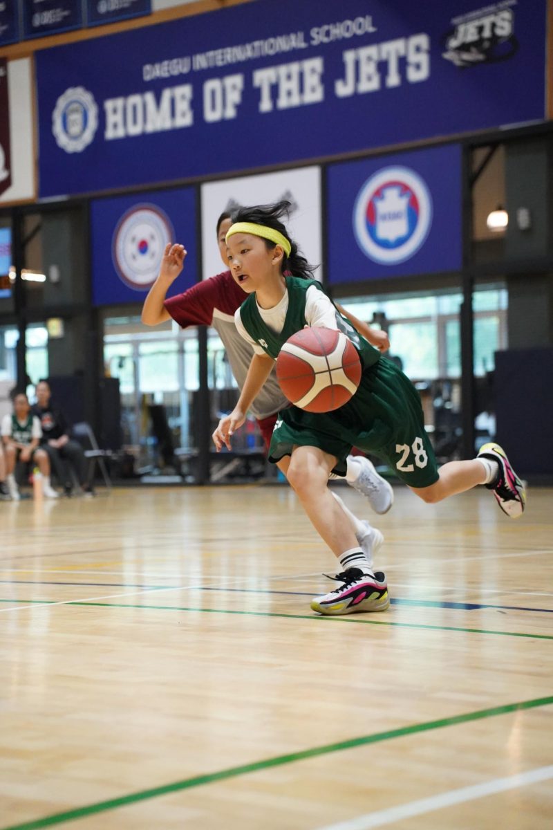 Fifth grader Amelia Kim charges down the court during a fast break opportunity. With a defender close behind, Kim stays determined while protecting the ball, looking out for an opening from her teammates.  