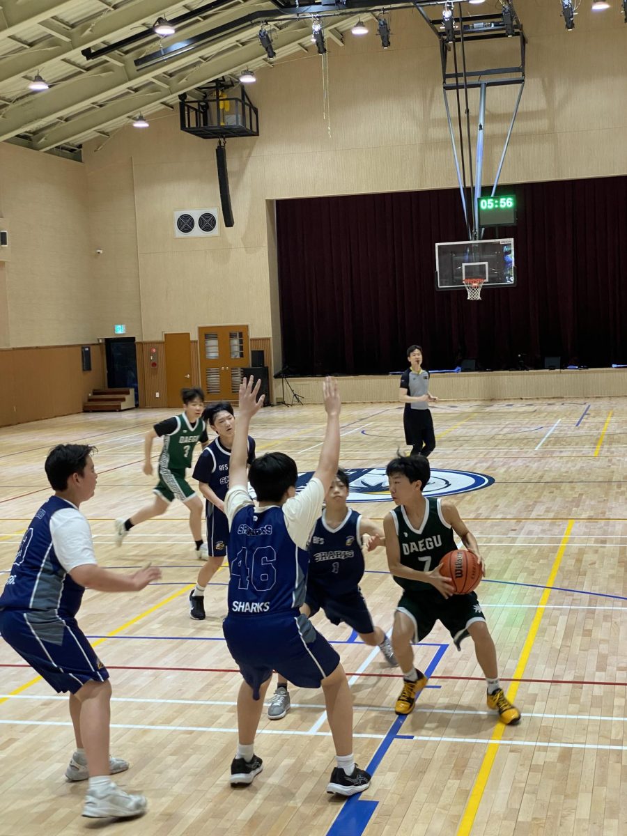 Seventh grader Steven Jang shields the ball as he cuts through defenses during a tense game. Jang pivots through the defenders and searches for an opening as the Sharks tighten their defenses around him. 