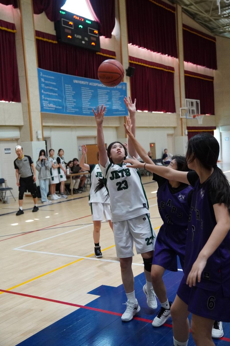 Seventh grader Kyla Ahn stretches toward the basket through heavy defensive pressure as she attempts a contested layup. Despite the crowd in the paint, Ahn keeps her focus locked on the ball while fighting for the finish.