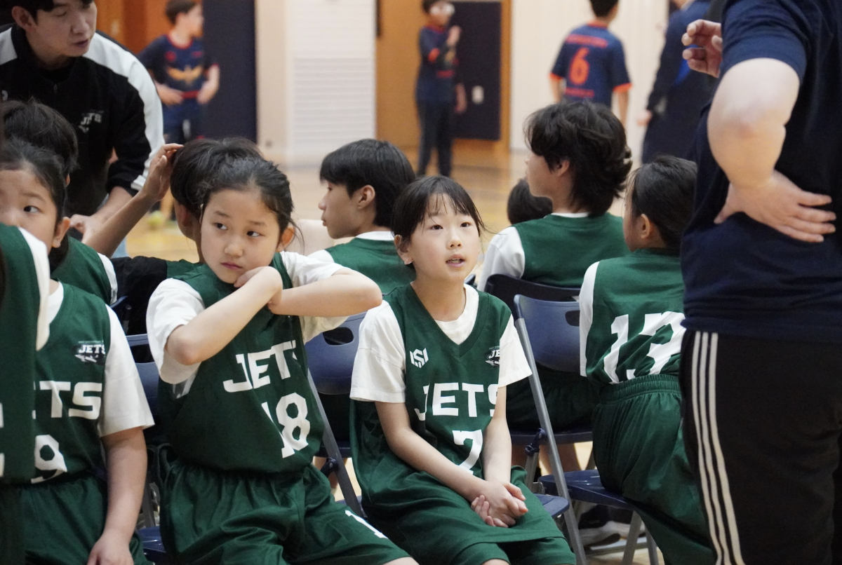 Third grader Lucy Kim and fourth grader Evelyn Hwang huddle in during a timeout, locking in on their game plan and syncing their roles on the court. Building coordination and teamwork, they regroup on the sidelines.