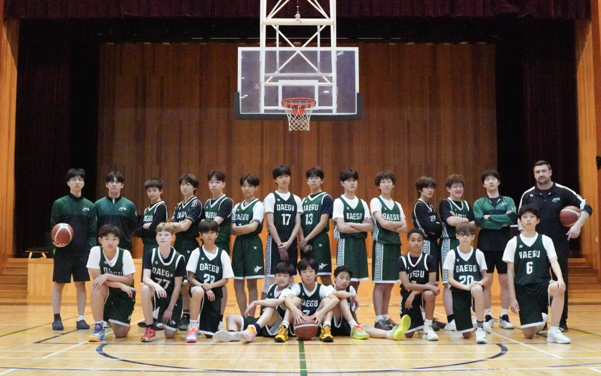 The DIS middle school boys basketball team gathers beneath the hoop as players and coaches prepare for the season ahead. With arms crossed and basketballs in hand, the Jets display confidence, unity and determination for the challenges ahead.
