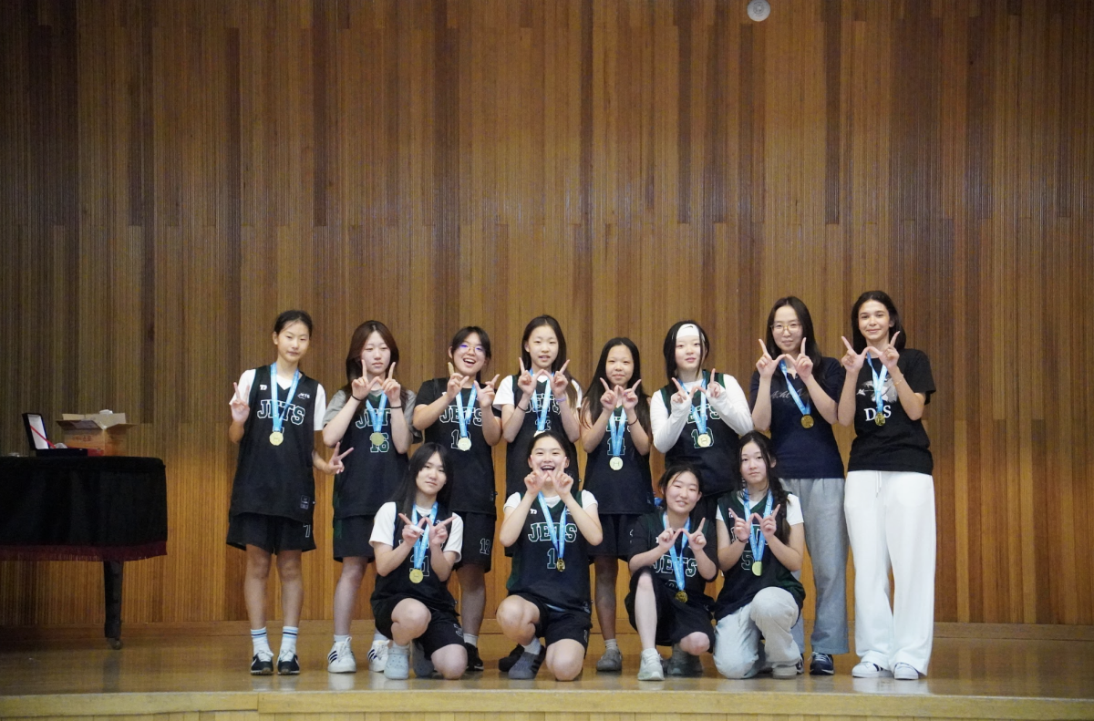 The JV girls basketball team celebrates their first-place finish after an undefeated tournament run. Players proudly display their gold medals following a championship performance fueled by teamwork and determination.