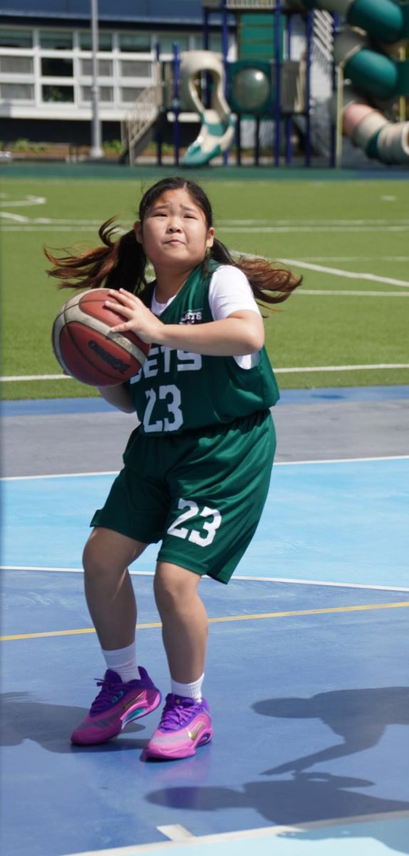 Fourth grader Violet Lee squares up for a mid-range shot, setting her feet with precision as her teammates create space with a well-timed screen. With a clear look at the rim, Lee prepares to release the ball. 