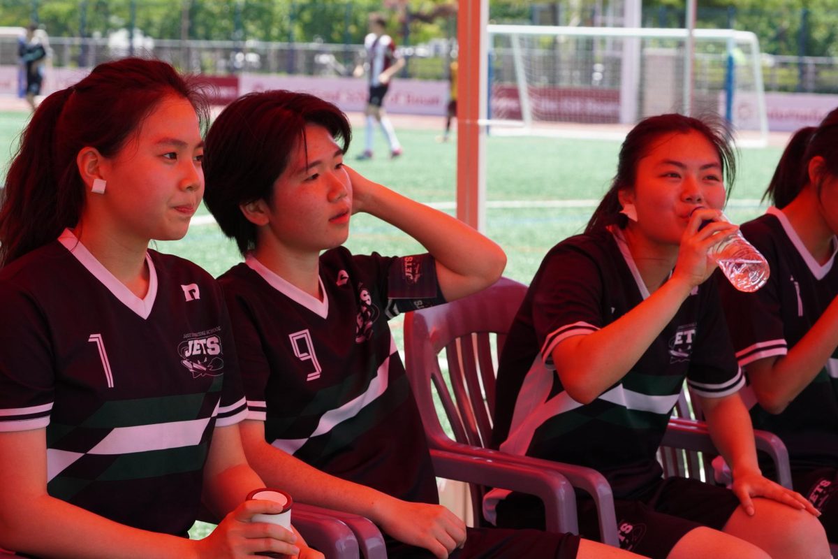 The DIS girls gather on the sidelines to regroup after a demanding stretch against ISB. During a brief break in play, players refocus their attention and encourage each other as they prepare for the next section of the match.
