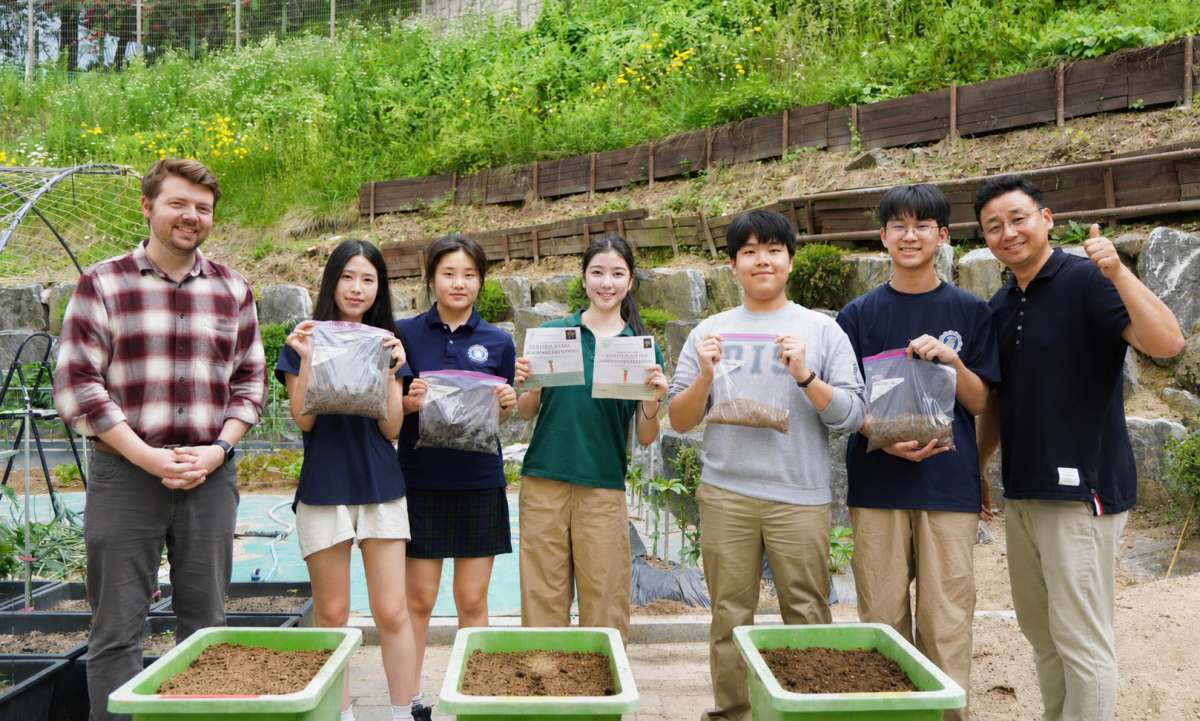 Eco-Lution members, along with advisor Mr. Coleman and Facility & Faculty Housing Director Mr. Bae, celebrate a successful day in the field. Members tested coffee ground biofertilizer as part of the club’s effort to recycle waste into resource in the DIS garden.